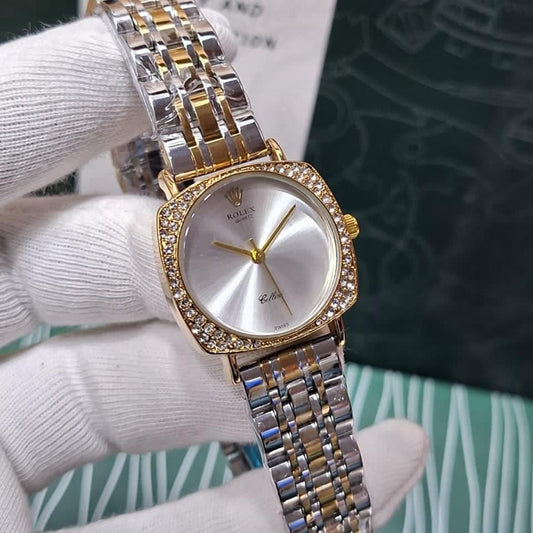 Gold and silver watch held by a gloved hand with a blurred background