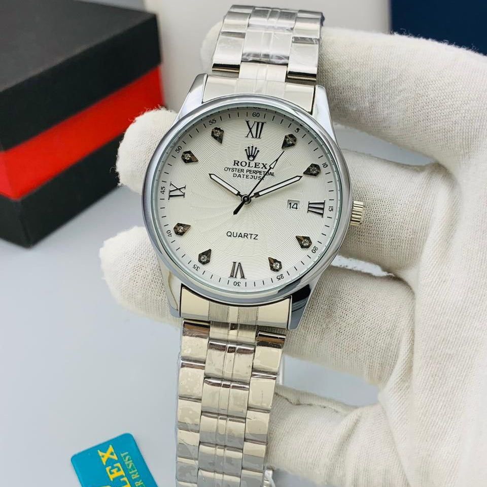 Silver wristwatch with white dial on a gray surface, featuring a Rolex tag.