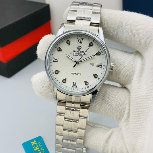 Silver wristwatch with white dial on a gray surface, featuring a Rolex tag.