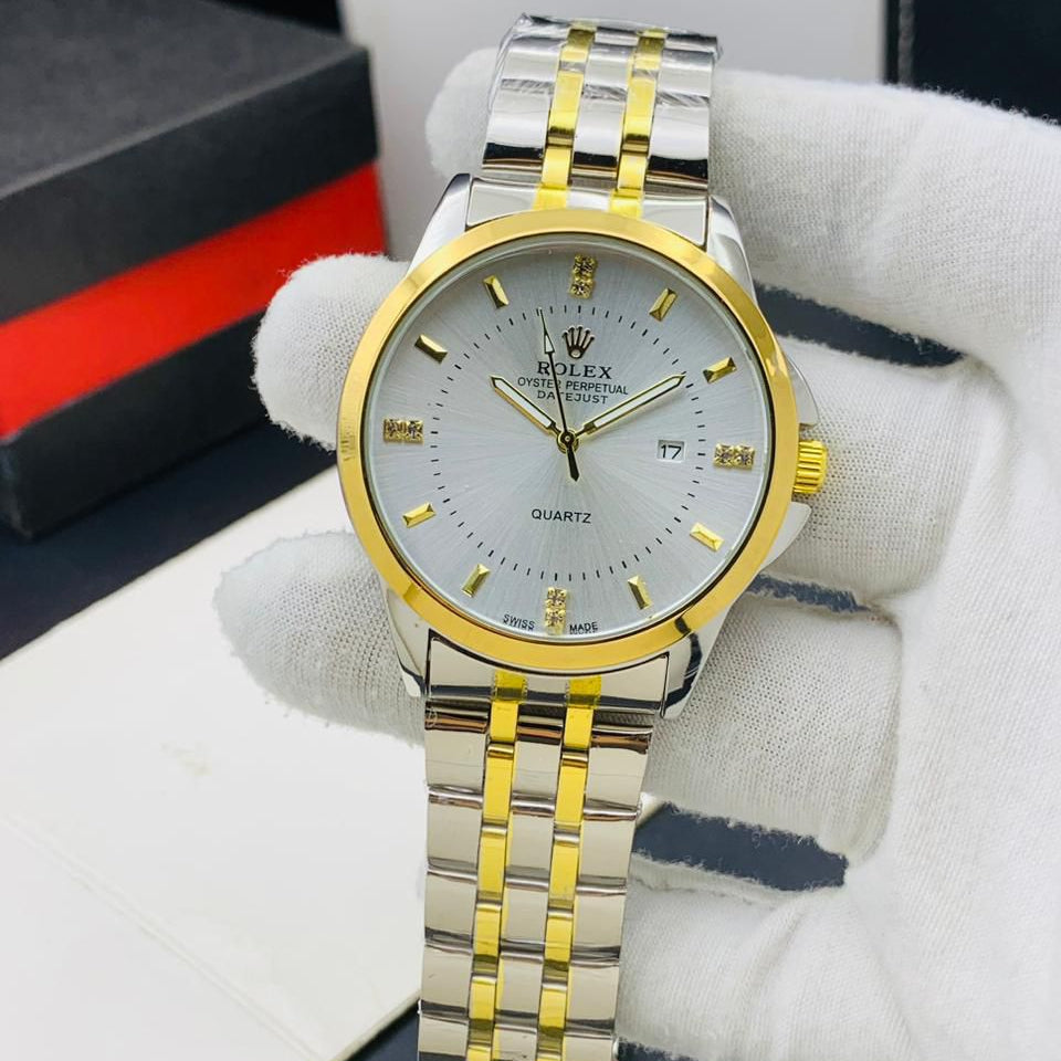 Rolex watch with gold and silver band held by a gloved hand, with a blurred background.