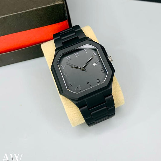 Black square watch on a stand with a box of additional watches in the background