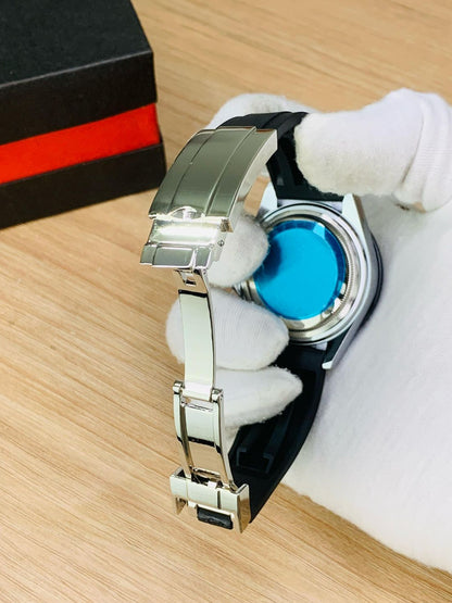 Watch with a blue face and silver band held by white gloves on a wooden surface.
