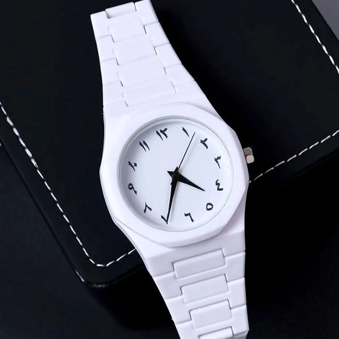 White wristwatch with a black face on a dark background