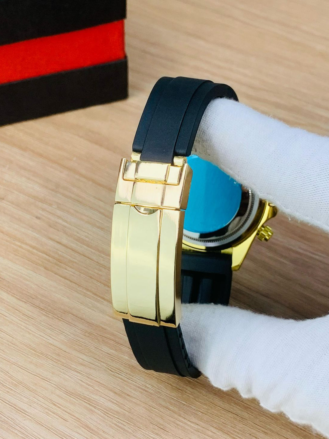 Luxury watch with gold case and black strap on a wooden surface